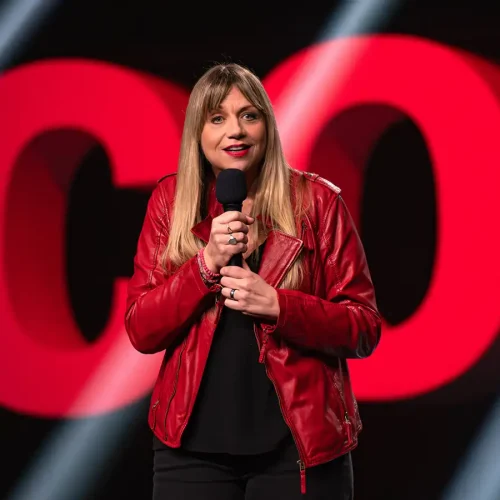 Comedian Mirja Regensburg auf der Bühne im Palladium Köln vor dem leuchtenden Schriftzug „Die besten Comedians Deutschlands“.