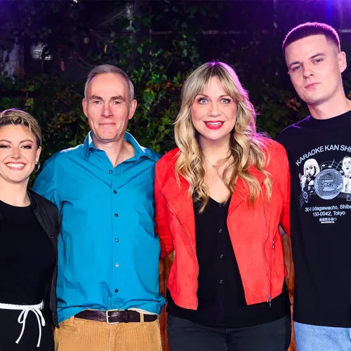 Komikerin Mirja Regensburg im roten Sakko lächelt mit Tahnee, Johann König und Alex Stoldt vor einer grünen Hecke beim ZDF Comedy Sommer.