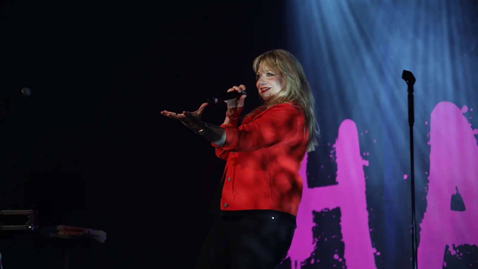 Mirja Regensburg singt leidenschaftlich auf der Bühne während ihrer HAPPY Tour vor pinkem Hintergrund-Logo