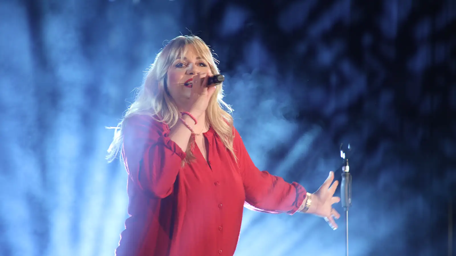 Mirja Regensburg singt leidenschaftlich auf der Bühne während ihrer HAPPY Tour im roten Outfit vor blauem Licht