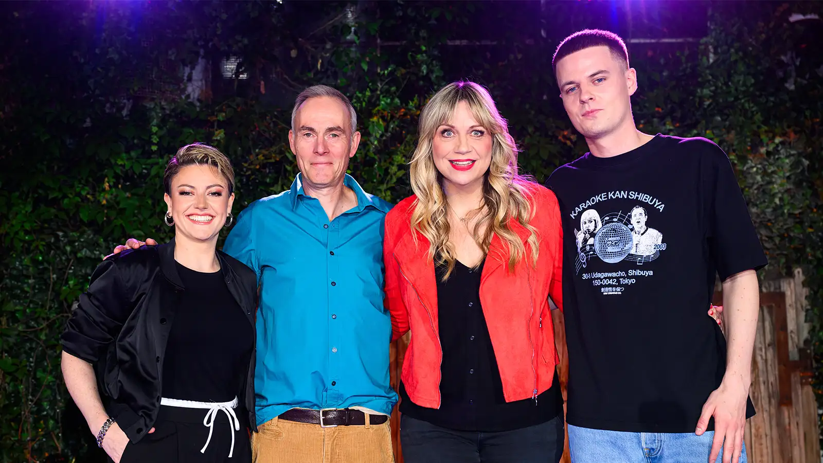 Mirja Regensburg im roten Sakko lächelt mit Tahnee, Johann König und Alex Stoldt vor einer grünen Hecke beim ZDF Comedy Sommer